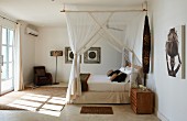 Himmelbett mit Moskitonetzen in Hotelzimmer mit sparsamer Möblierung im afrikanischen Stil
