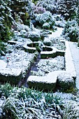 Winterlich beschneite Gartenlandschaft mit geometrisch angelegten Heckenstrukturen