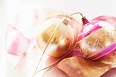Gold and pink Christmas baubles lying on ribbon