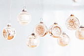 Row of suspended silver glass baubles with embossed patterns in convex sides