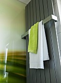 Grünes und weisses Handtuch über Bügel an Handtuchtrockner aus Edelstahl im Duschbereich eines modernen Bades