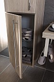 A tall, oak-effect cupboard with stainless steel handles with the lower door open to show towels; floor and wall covered in brown quiet tiles to match the furniture