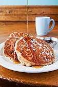 Pancakes with icing sugar and maple syrup