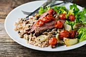 Grain salad with beef steak and oven-roasted vegetables