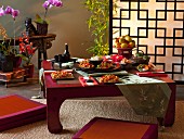 Gedeckter Tisch mit asiatischen Gerichten in asiatischem Ambiente