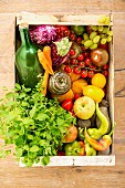 Fruit, vegetables, apple juice and herbs in a crate