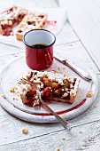 A slice of plum cake with coconut crumbles and a mug of coffee