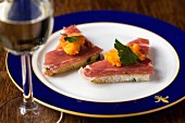 Toast triangles topped with smoked ham and carrot cream