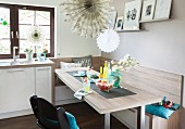 A dining area with a robust, grey-beige wooden look with a corner bench and child's highchair in an open plan kitchen