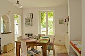 Friendly dining room with set table in centre; fitted shelving and bench in niches