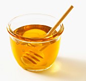 Honey in a glass bowl with a wooden spoon
