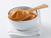 Peanut butter in a bowl and on a wooden spoon