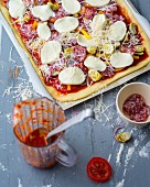 Pizza with vegetables, salami and mozzarella being made
