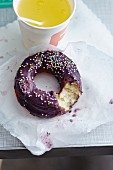 A doughnut with chocolate glaze and sugar sprinkles served with a soft drink