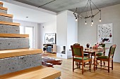 Eichenmöbel mit gedrechselten Beinen und rustikale Ast-Leuchte im offenen, modernen Wohnraum; Sichtbetonstufen mit Holzbelag im Vordergrund