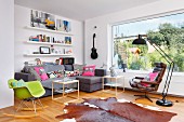 Green classic rocking chair, corner sofa and leather armchair in front of panoramic window in open-plan interior