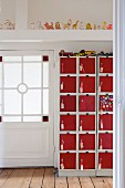 Toy cars on top of eye-catching locker cabinet with red doors in hallway with beautiful lattice door and row of squeaky toys on roof beam