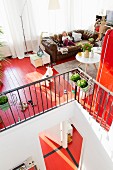 Living room on gallery with brown leather sofa and red-painted wooden floor