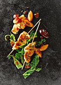 Chicken breast skewers with savoy cabbage, plums, bacon, shredded herb pancakes and tomato sauce