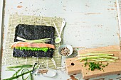 Zutaten für Uramaki-Sushi und unfertige Sushi-Rolle auf Sushi-Matte