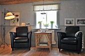 Zwei schwarze Ledersessel mit filigranem Holztisch in gemütlichem skandinavischem Landhausambiente