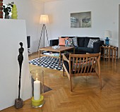 Armlehnstuh, Couchtisch und Beistelltisch-Set aus Holz, Teppich und Kissen mit geometrischem Muster im Wohnzimmer, vorne Skulptur und Windlicht