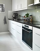 weiße Designerküche mit Spritzschutz und weiß gestrichenem Dielenboden