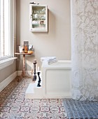 Candlesticks on steps leading to bathtub and ornamental tiled floor in traditional bathroom