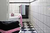 Perspektive auf freistehende Wanne und farblich abgestimmte Handtücher in schwarzweiss gefliestem Badezimmer