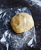 Shortcrust pastry being wrapped in clingfilm for chilling