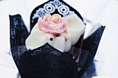 An elegant praline decorated with a rose in a black paper case