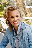 A young blonde woman outside wearing a denim shirt