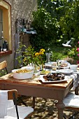 Mit Muscheln, Pommes und Zitronenscheiben gedeckter Holztisch im Garten eines französischen Landhauses