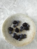 Fresh blueberries and blackberries in a natural stone bowl