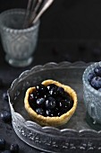 Pudding tartlet with blueberries on a pewter tray