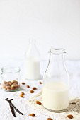 Glass bottles of almond milk, almonds and vanilla pods