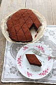A chocolate cake cut into diamond shaped slices on a wooden table with a lace cloth