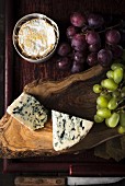 Various types of cheese and grapes on a wooden surface