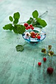 Various berries with leaves in a glass bowl