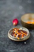 Globules in the lid of an old pill tin with dried marigold petals and a dried rose petal