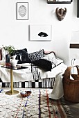 Sofa with blankets and hand-made, black and white scatter cushions on pale, patterned woollen rug