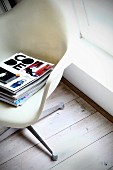 Stack of magazines on Plastic Armchair (Eames)