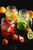 Various types of fruit juice with fresh fruits in glass jars