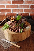 Sliced roast beef with chips on a round wooden block