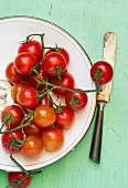 Cherry tomatoes on a plate next to a knife