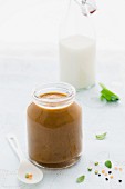A jar of baby lentil purée with a bottle of milk in the background