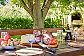 A sumptuous supper platter, a basket of bread, fruit and nuts on a garden table