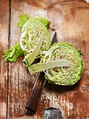 Organic savoy cabbage, halved, on a wooden surface