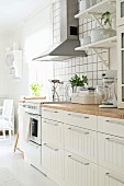 Scandinavian kitchen counter below bracket shelves and extractor hood