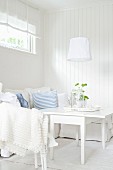 Seating area in white, Scandinavian interior with sofa and table with folding side leaves